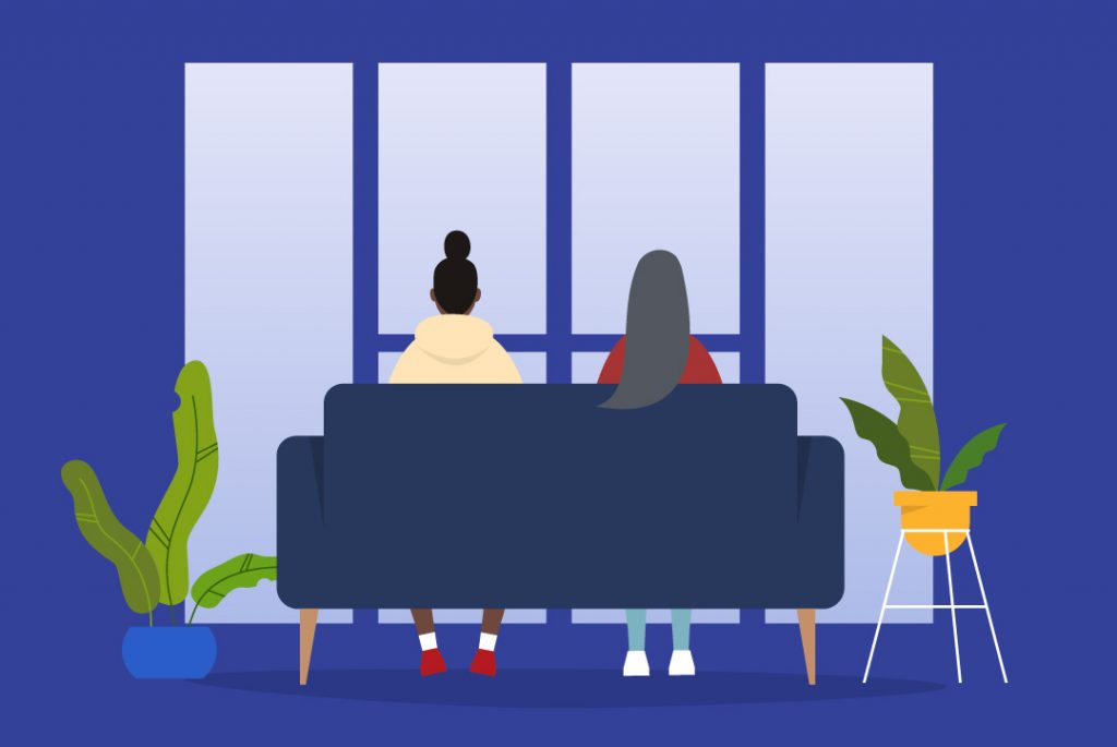 two people sitting on a couch facing the window